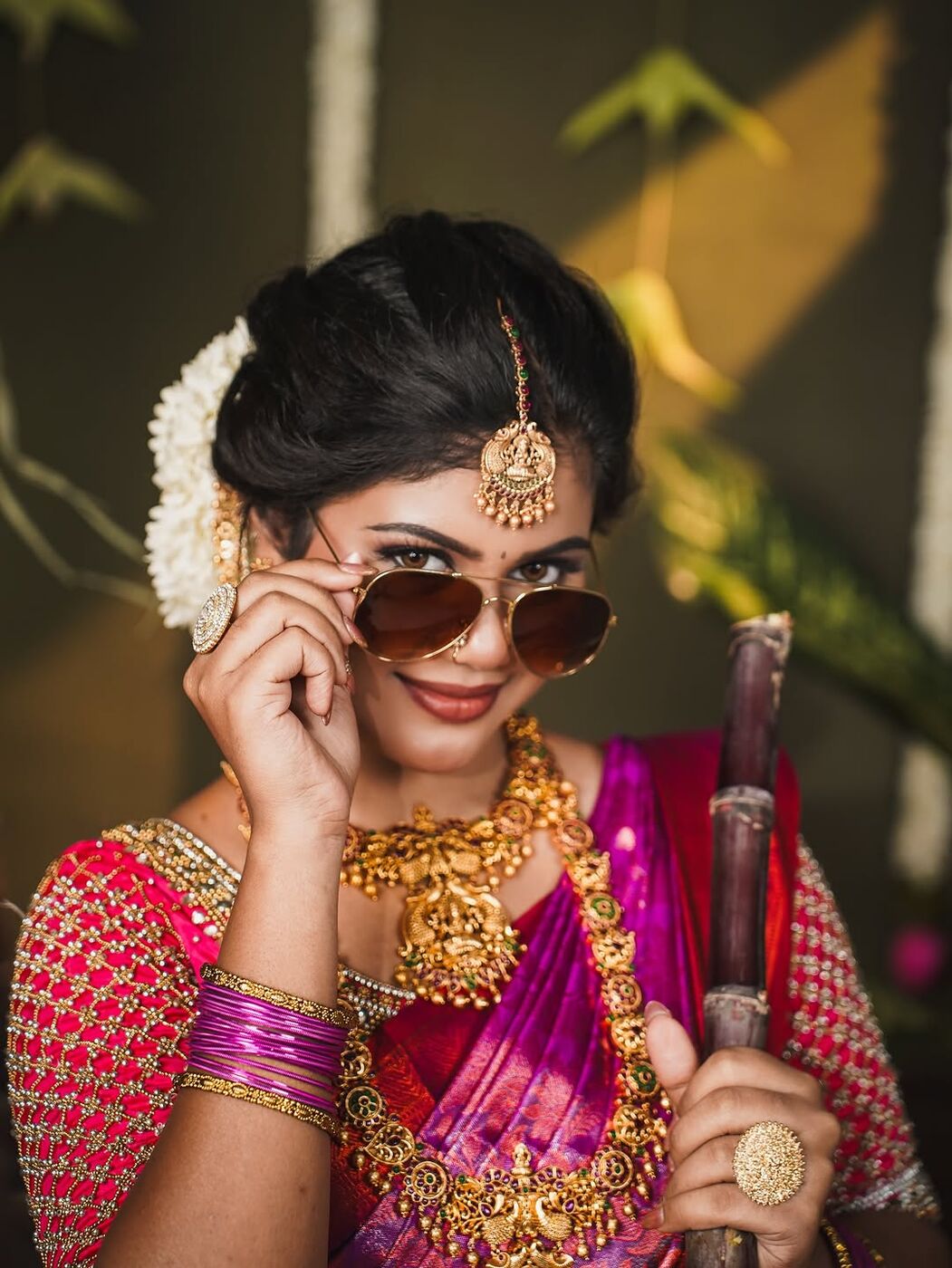 Playful bride in pink silk saree lowering her sunglasses