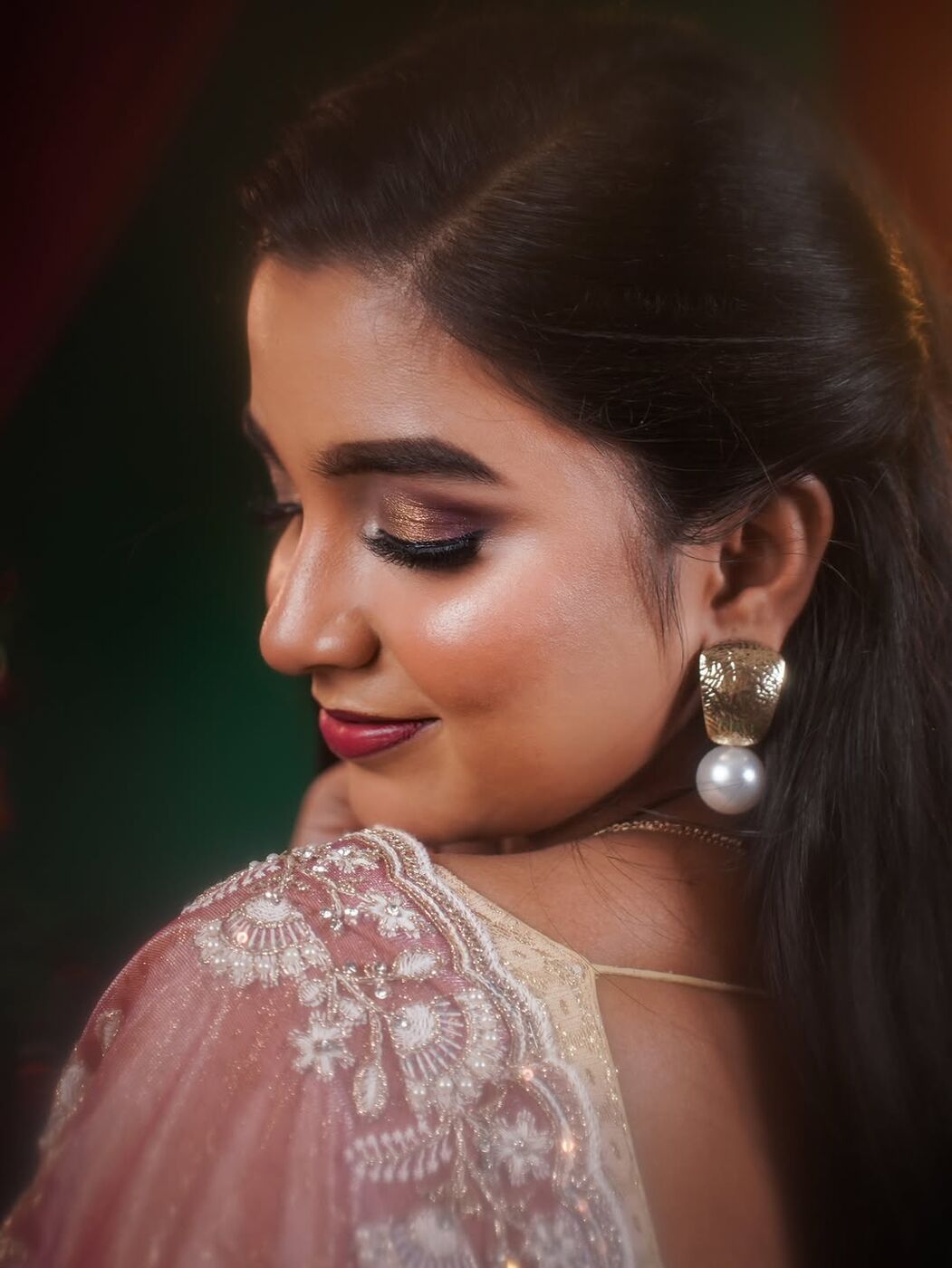 Close-up of glowing skin, winged liner and pearl earring